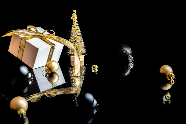 圣诞装饰。白色的礼物与金色的弓，金色的球和新年树在圣诞装饰在黑暗的背景贺卡。圣诞背景与文字空间。图片下载