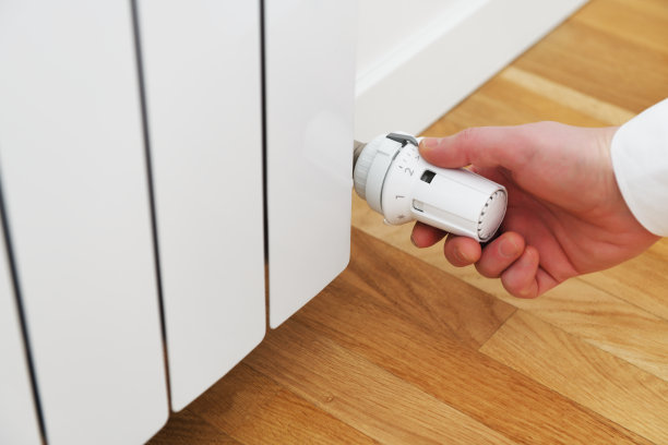 有人控制暖气。手动调节房间暖气暖气片温控器阀门。图片下载