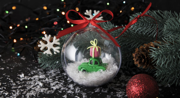 透明圣诞球与玩具车和礼物在黑暗的背景与彩色灯图片下载