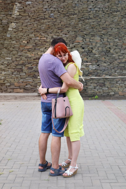 在夏天的一天，一对年轻的情侣在户外相遇时拥抱在一起图片下载