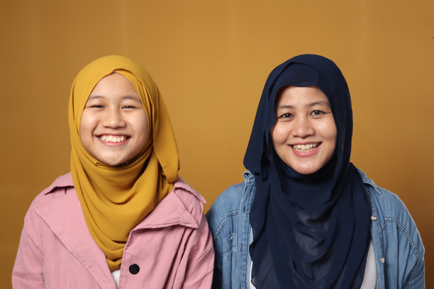 人们和家庭观念-幸福微笑的亚洲穆斯林母亲拥抱女儿在黄色的背景图片下载