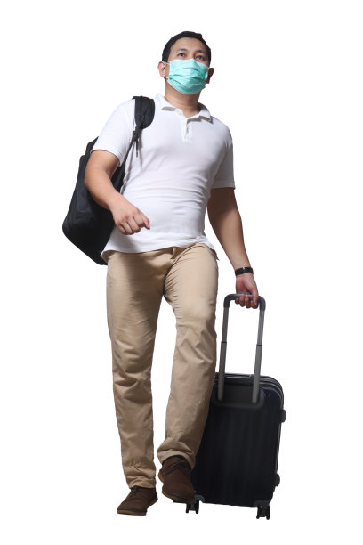 戴口罩的亚洲男子在新冠肺炎疫情期间拖着行李箱行走，穿着休闲衬衫和背包，全身画像图片下载