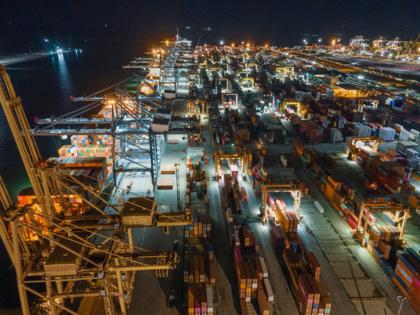 日落时分，无人机吊车桥在船厂拍摄，物流进出口和运输行业背景图片下载