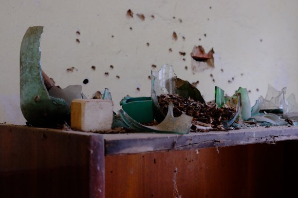 碎玻璃器皿的碎片。罐头和瓶子的碎片被用作射击目标。墙上有弹孔。射击瓶子的后果。图片下载