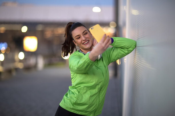 晚上在街上用手机拍下健身后休息的女性图片下载
