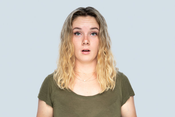 肖像的震惊年轻女子看相机与负面的面部表情在灰色的背景图片下载