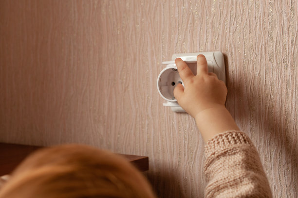 孩子玩一个出口，拉他的手到它，他的手指。这孩子在家有危险。婴儿的手指插在插座里。图片下载