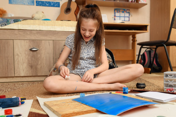 女孩在家里画画，进行艺术创作，用纸、颜料和画笔制作创造性的艺术品图片下载