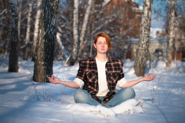 年轻女子在雪山上摆莲花姿势。图片下载