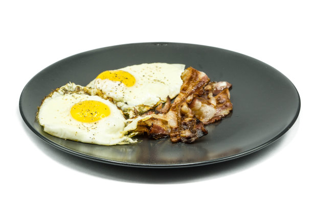 鸡蛋和培根放在盘子里，孤立在白色背景上图片下载