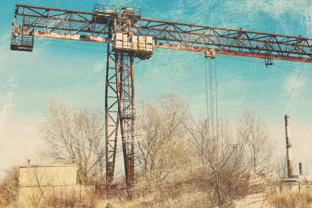 旧的，生锈的门式起重机在铁路上，一个废弃的混凝土工厂。危机、经济崩溃和生产能力的关闭导致了崩溃。全球灾难。一张古老照片的效果。图片下载