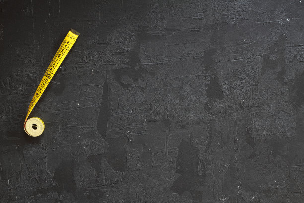 黄色卷尺，用于工具轮盘或尺。卷尺以厘米为单位测量模板。磁带仪表设置隔离在黑色背景。图片下载