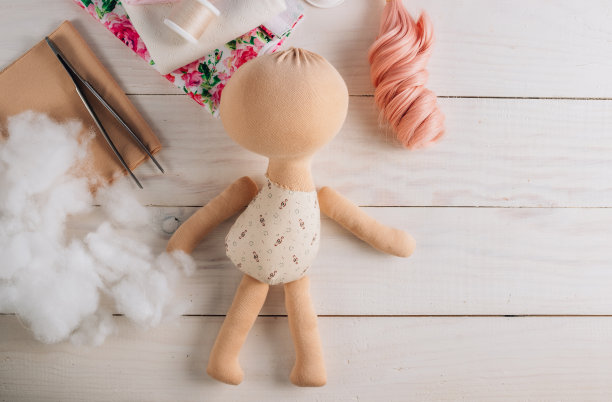 纺织娃娃在缝制过程中，以白色木制背景为辅料和材料图片下载