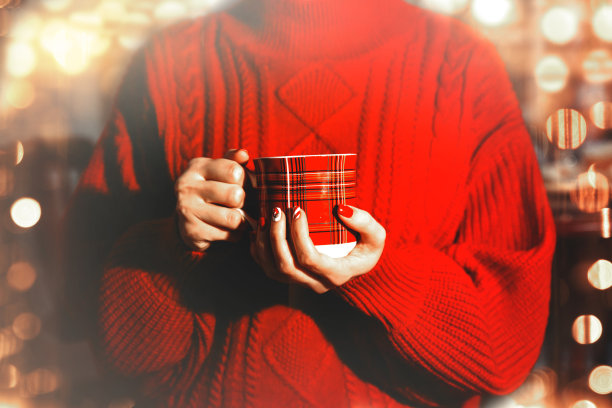 一个穿着红毛衣的女孩拿着一个圣诞马克杯图片下载