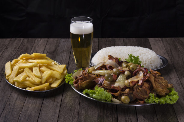 一张炸鸡配乡村洋葱和培根的照片，配上一杯清爽的啤酒，炸薯条和白米饭。水平的美食摄影。图片下载