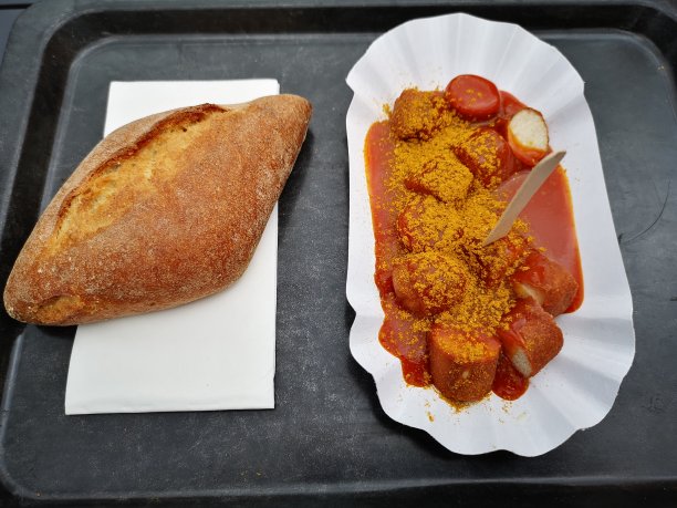 传统的德国咖喱香肠，香肠和咖喱，一次性纸盘上的新鲜面包/面包。图片下载