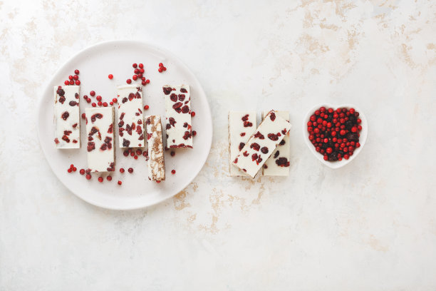 白巧克力饼干太妃糖，蔓越莓和杏仁放在盘子和旁边。美味的圣诞治疗。图片下载