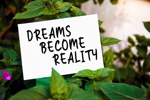 梦想成为现实励志信息写在纸上绿色的花园和植物的背景。追逐梦想，成功和坚持。图片下载