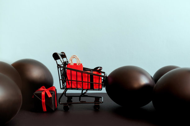 红色和黑色礼盒在购物车上的蓝色背景与小玩意，拷贝空间。“黑色星期五”的概念图片下载