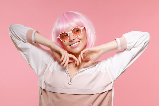 时尚肖像年轻快乐的女人与粉红色的头发和眼镜，望着别处和梦想的东西图片下载