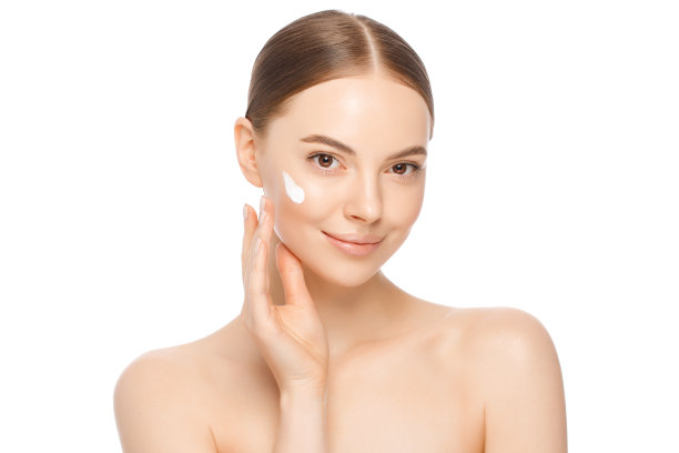 年轻美丽的女子将面霜涂在颧骨作为早晨例行公事的一部分，孤立在白色的背景。女性护肤理念图片下载