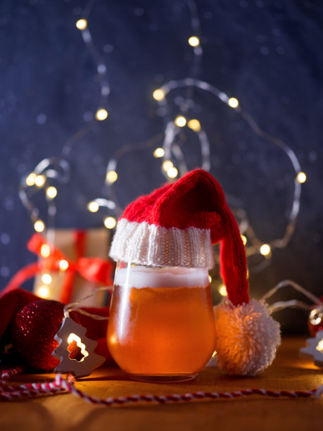 一杯清淡的圣诞啤酒和创造性的新年装饰在桌子上的圣诞礼盒，气球和花环图片下载