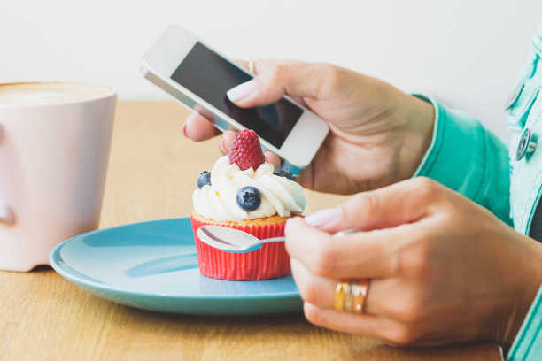 一个女人拍了张照片，上面有卡布奇诺和盘子里的纸杯蛋糕图片下载