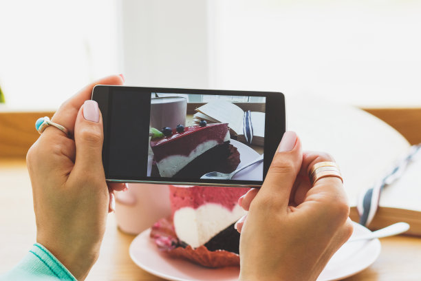 一个女人拍了张照片，盘子里有一杯卡布奇诺和一块甜点图片下载