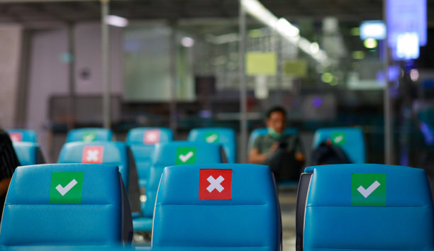 候诊室里的蓝色椅子排成一列，椅子上有标志，表示新冠肺炎期间的社交距离图片下载