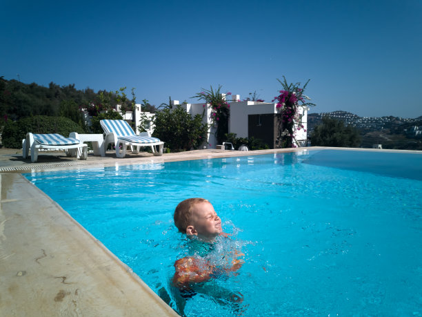 蹒跚学步的小男孩穿着救生衣跳进游泳池图片下载