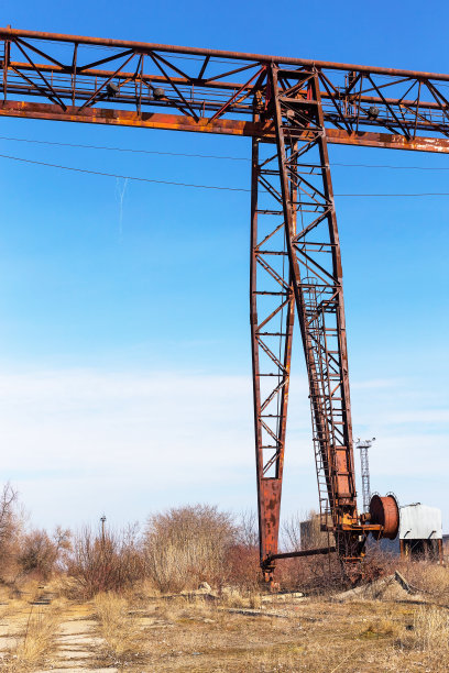 旧的，生锈的门式起重机在铁路上，一个废弃的混凝土工厂。危机、经济崩溃和生产能力的关闭导致了崩溃。全球灾难。一张古老照片的效果。图片下载