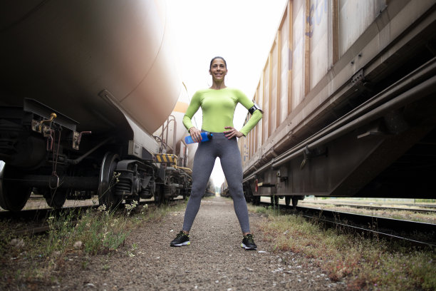 性感女运动员骄傲地站在火车之间，对着镜头微笑的肖像。健身和运动。图片下载