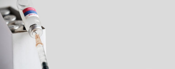 瓶盖上插着注射器和一盒安瓿的俄罗斯新型疫苗，用于防止病毒株感染。白色孤立背景，选择性聚焦，横幅。图片下载