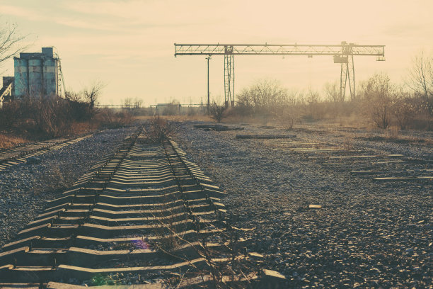 旧的，生锈的门式起重机在铁路上，一个废弃的混凝土工厂。危机、经济崩溃和生产能力的关闭导致了崩溃。全球灾难。一张古老照片的效果。图片下载