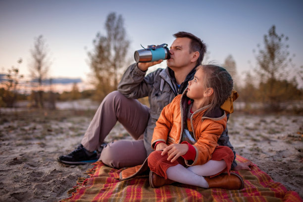 家庭秋天走。可爱的女孩和她的父亲坐在格子间在金色的森林在秋天图片下载