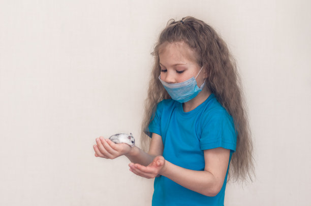 一个戴着面具的学龄前女孩抱着一只白色的准噶尔仓鼠看着他的肖像。工作室白色背景。宠物的啮齿动物。游戏儿童和动物。隔离病毒隔离。图片下载