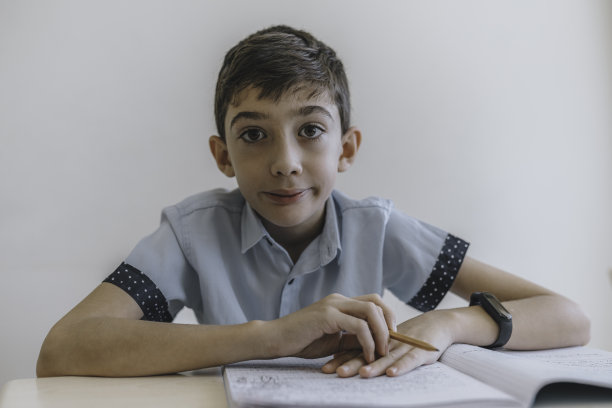 一个快乐的小男孩坐在教室的课桌前图片下载