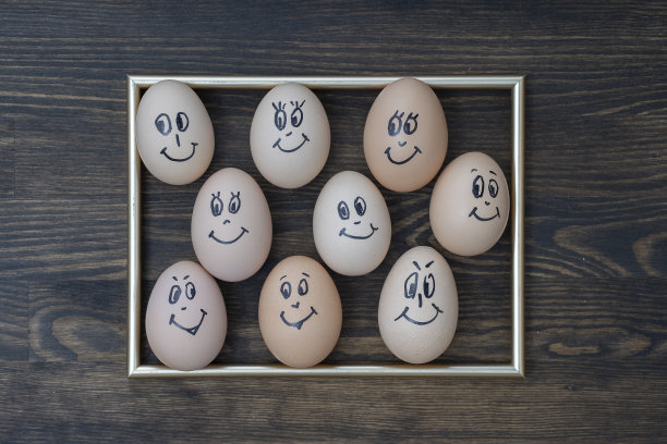 图片的金色框架和许多有趣的鸡蛋微笑在黑暗的木墙背景。鸡蛋家庭情感面部肖像。概念有趣的食物图片下载