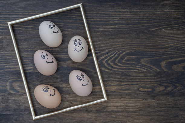 图片的金色框架和许多有趣的鸡蛋微笑在黑暗的木墙背景。鸡蛋家庭情感面部肖像。概念有趣的食物图片下载