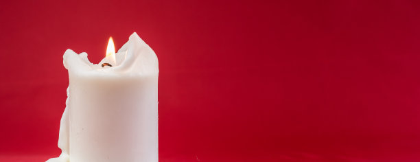 蜡烛燃烧。白色蜡烛集中燃烧单支蜡烛，红色背景图片下载