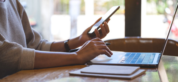 在办公室里拿着并使用移动电话和笔记本电脑的女商人图片下载