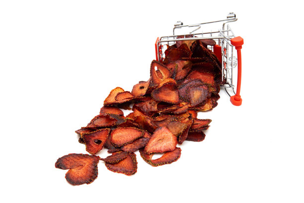 脱水草莓。干草莓片在玩具购物车孤立白色。图片下载