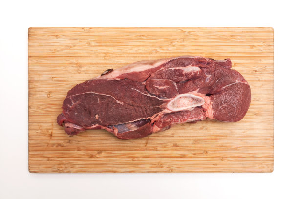 新鲜的大块肉。多汁的牛肉带骨汤在木砧板上，俯视图图片下载
