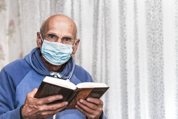 老秃顶智者戴着眼镜和防护面罩，手里拿着书读祈祷文图片下载