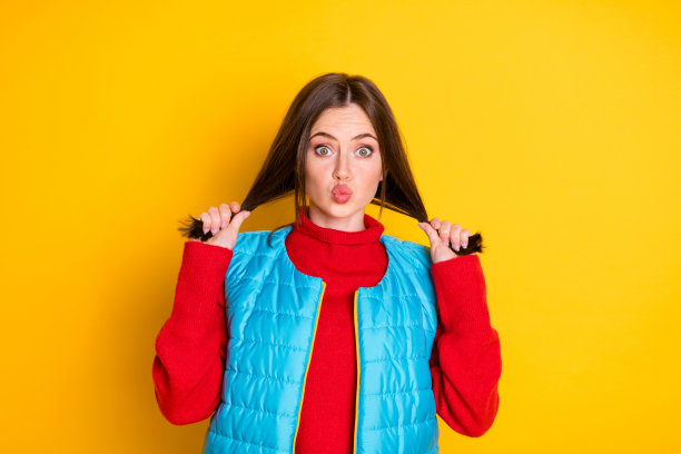 可爱的女孩的照片触摸她的头发享受强大的直发健康发送飞吻穿季节衣服孤立在明亮的光泽颜色背景图片下载