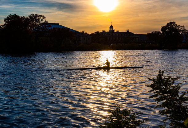 一个单独的划桨手在查尔斯河剪影在黑暗的秋天日落-剑桥，马萨诸塞州，美国。图片下载