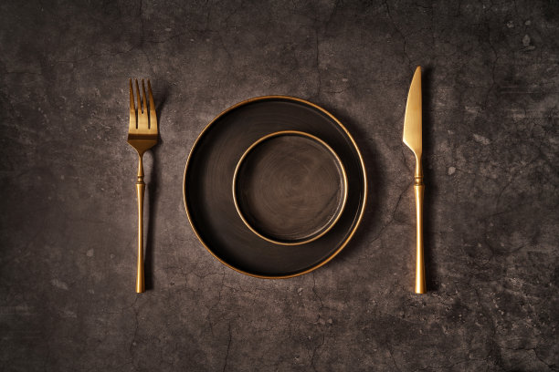 复古模板与旧金属盘子和金色的刀和叉在黑色的石头背景为概念设计。平的风格。图片下载