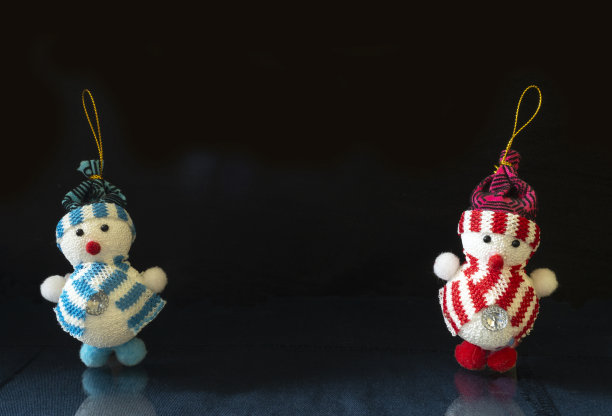 在黑色背景的玻璃桌子上的玩具雪人图片下载