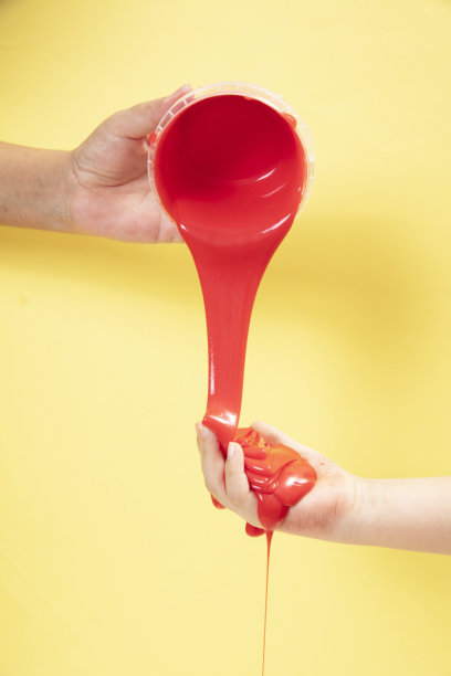 快乐的妈妈和她的儿子玩霓虹灯红色黏液玩具在黄色波普艺术背景。图片下载