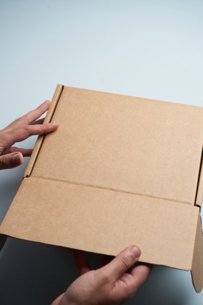女人双手打开空纸板箱，俯视图图片下载
